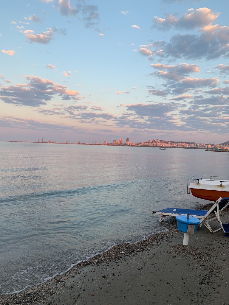 Sunrise over the beach in Durrës, Albania, with the city skyline across the bay